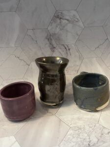 The image shows three clay vessels against a marbled background. 